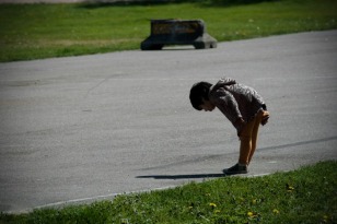 A child examines his own shadow on the ground.